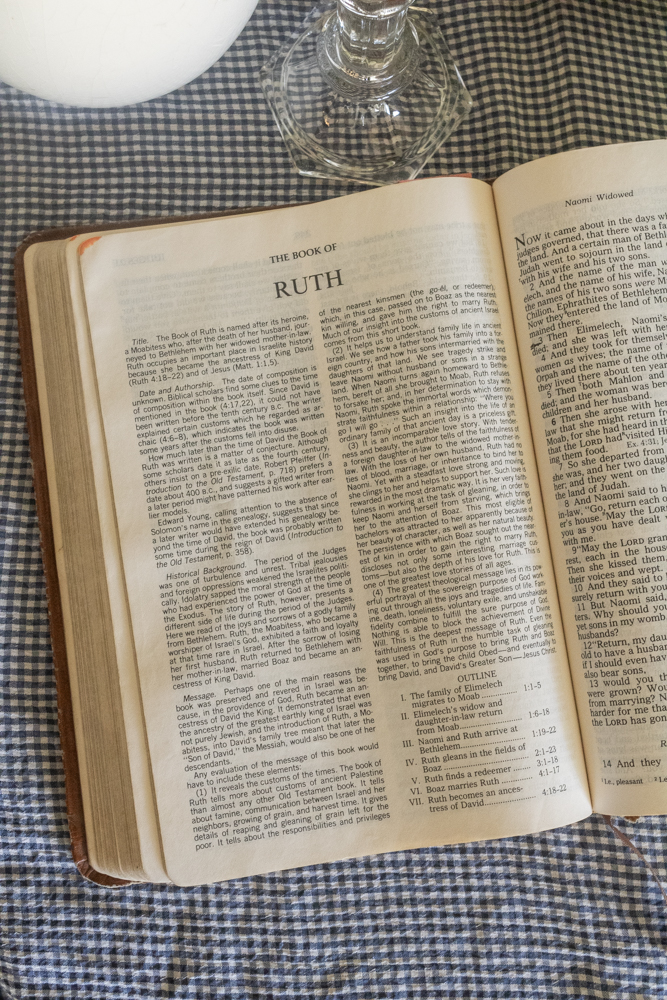 bible open to ruth chapter 1 on blue and white gingham tablecloth