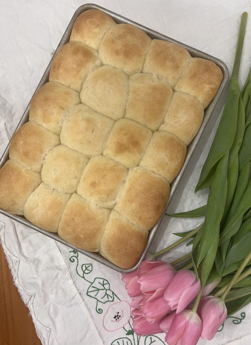 yeast rolls in metal pan on vintage embroidered table linen with pink tulips
