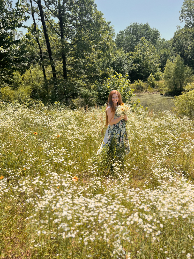 Girl in floral apron in wildflower field