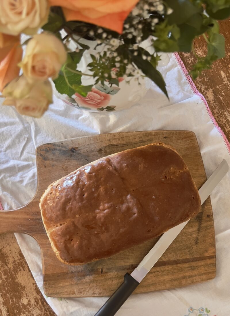 Whole loaf of gluten free yeast bread (sandwich) on wood cutting board and vintage tablecloth