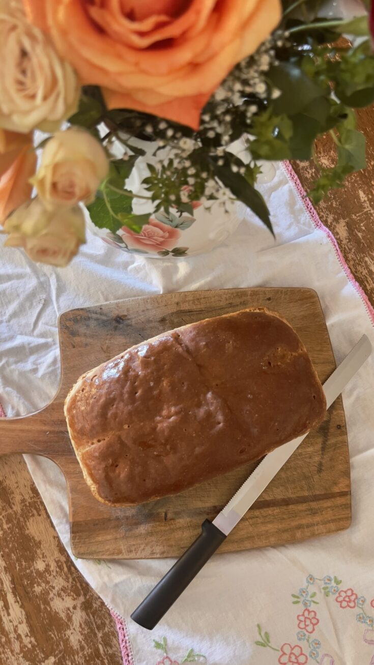 Whole loaf of gluten free yeast bread (sandwich) on wood cutting board and vintage tablecloth