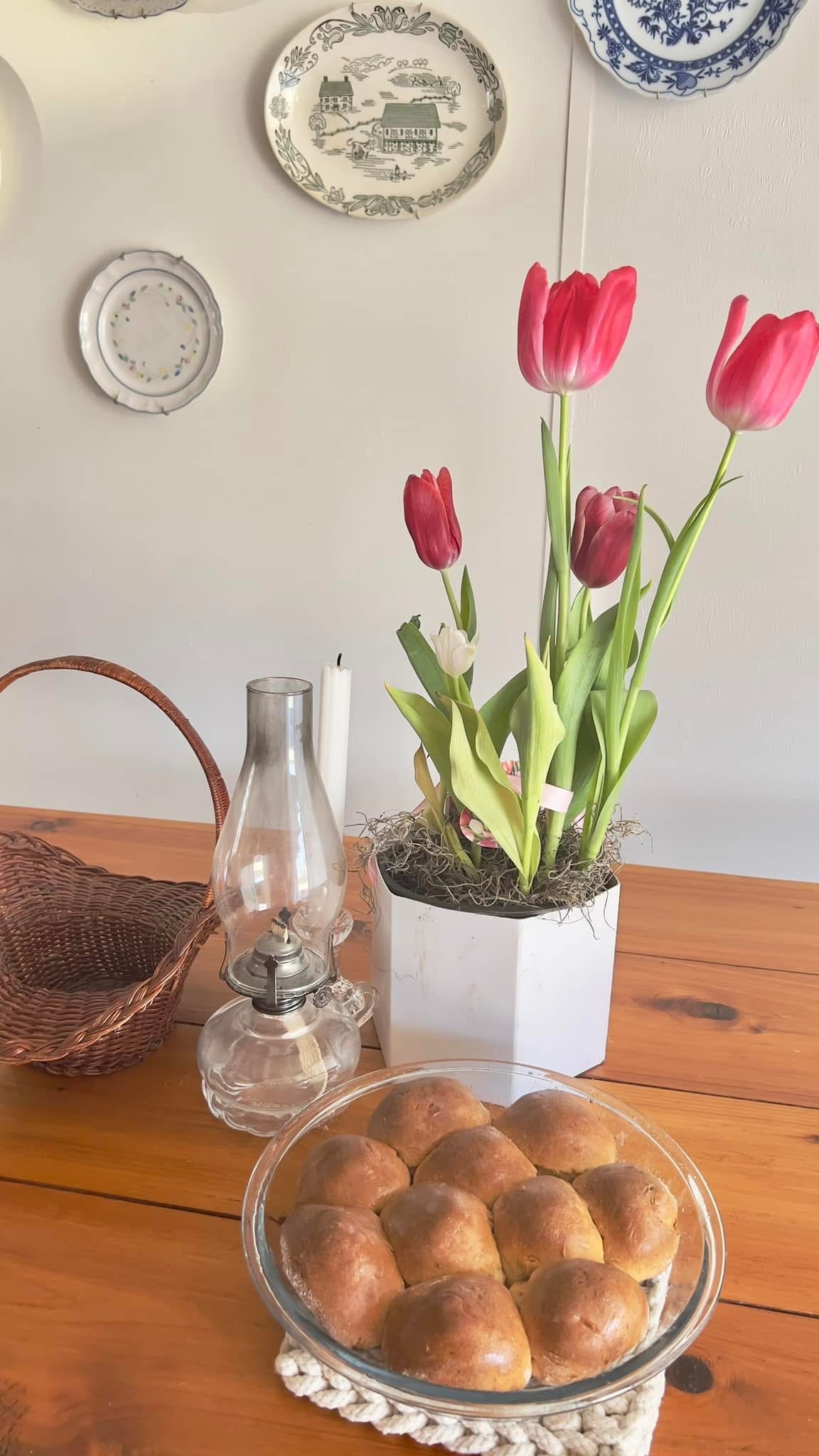 gluten free yeast rolls in glass baking dish on cedar table with pink tulips