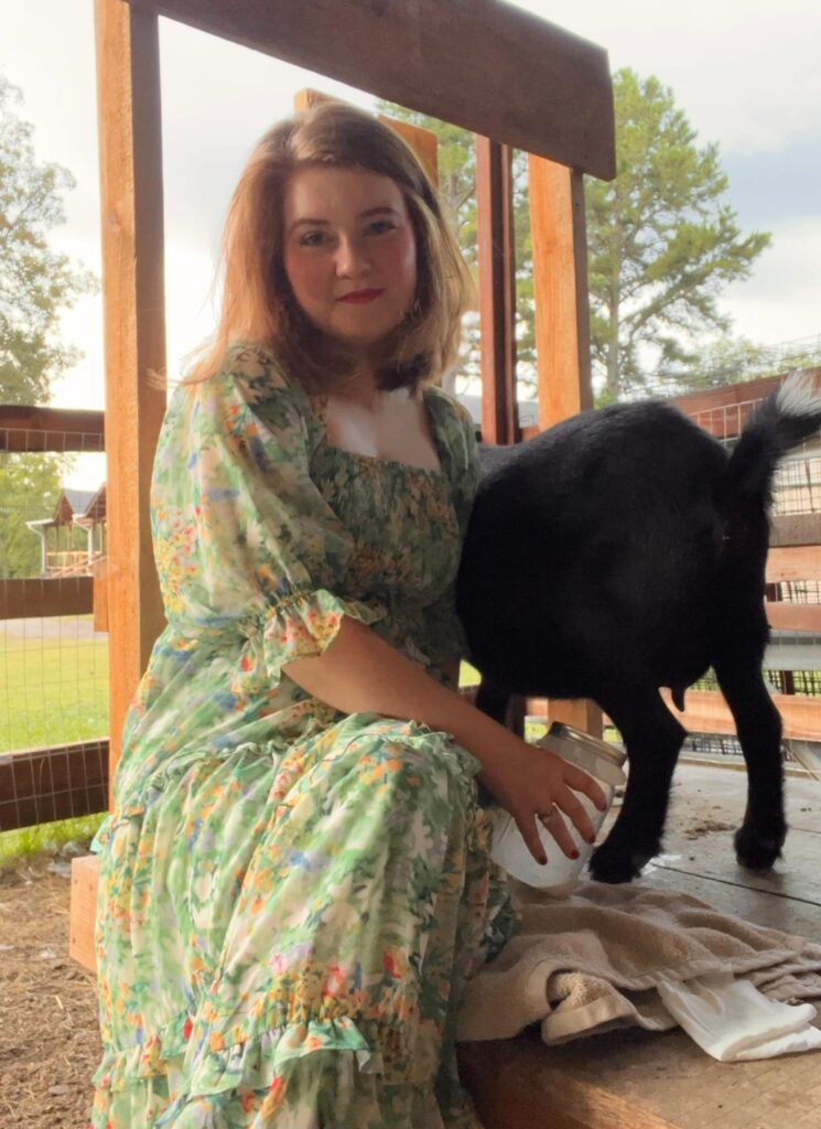 girl in green dress milking nigerian dwarf goat on DIY Goat Milking Stand