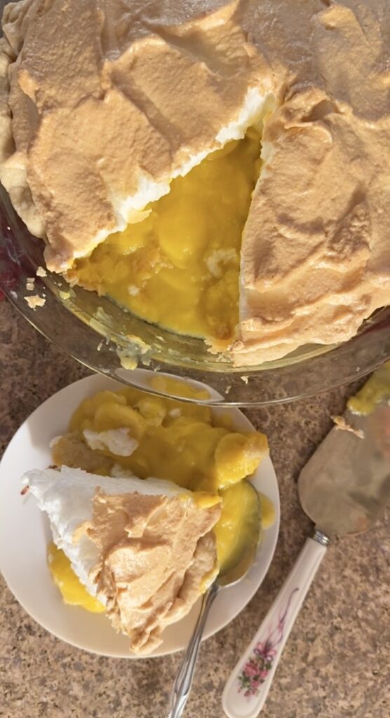 A banana cream pie sliced on a plate next to the pan of banana cream pie