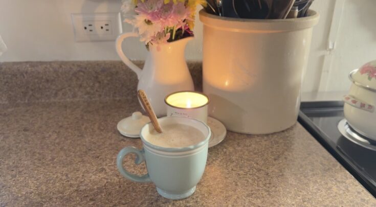 Sweet Cream and Honey Latte in a light blue mug with flowers and a lit candle behind