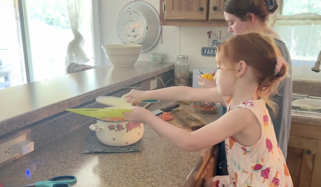 Little girl and mom chop oranges for orange marmalade