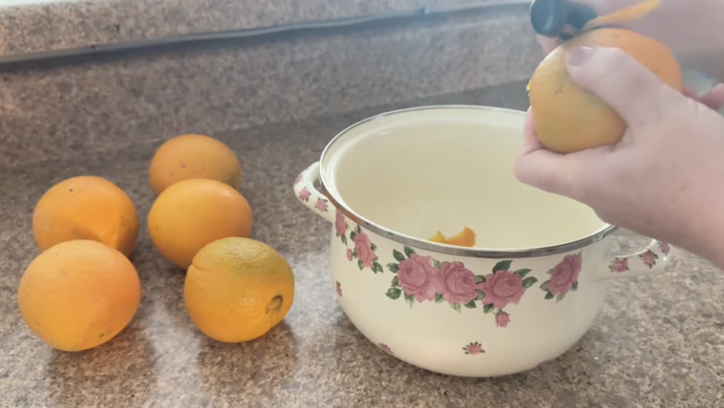 Peeling Oranges with a vegetable peeler into a rose enameled pot