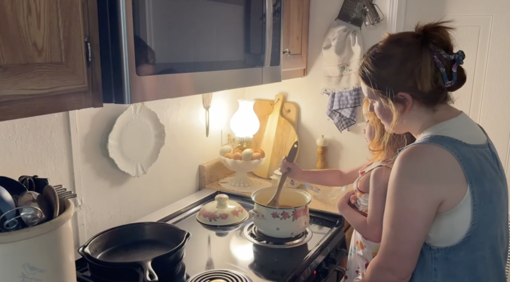Little girl and mom stir the sugar into the marmalade while it cooks.
