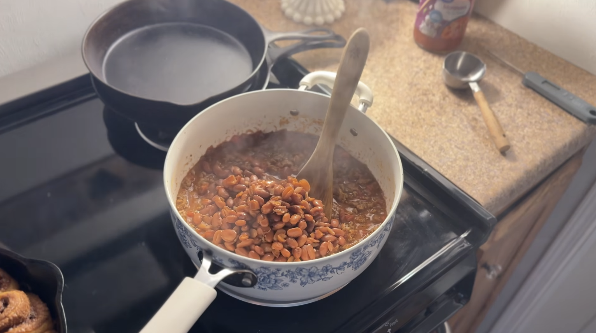 pioneer woman blue and white pot on stovetop while adding beans to chili