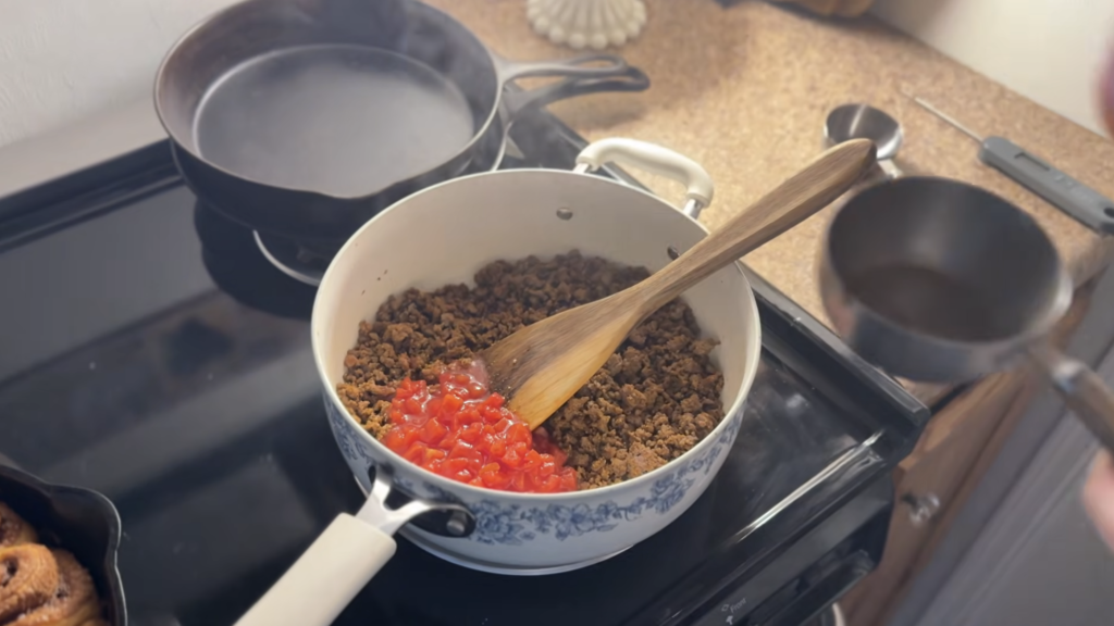pioneer woman blue and white pot on stovetop while adding tomato sauce